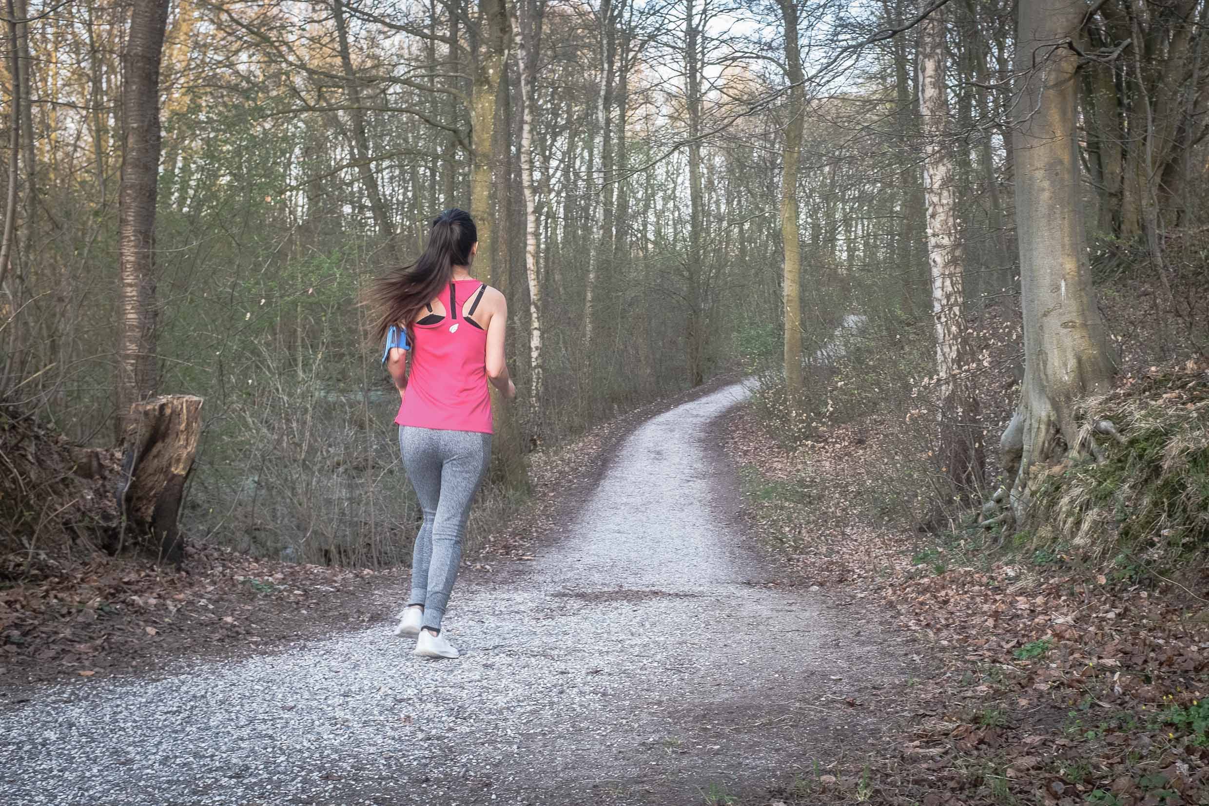 Arina running while listening to music on a gravel path in a forest