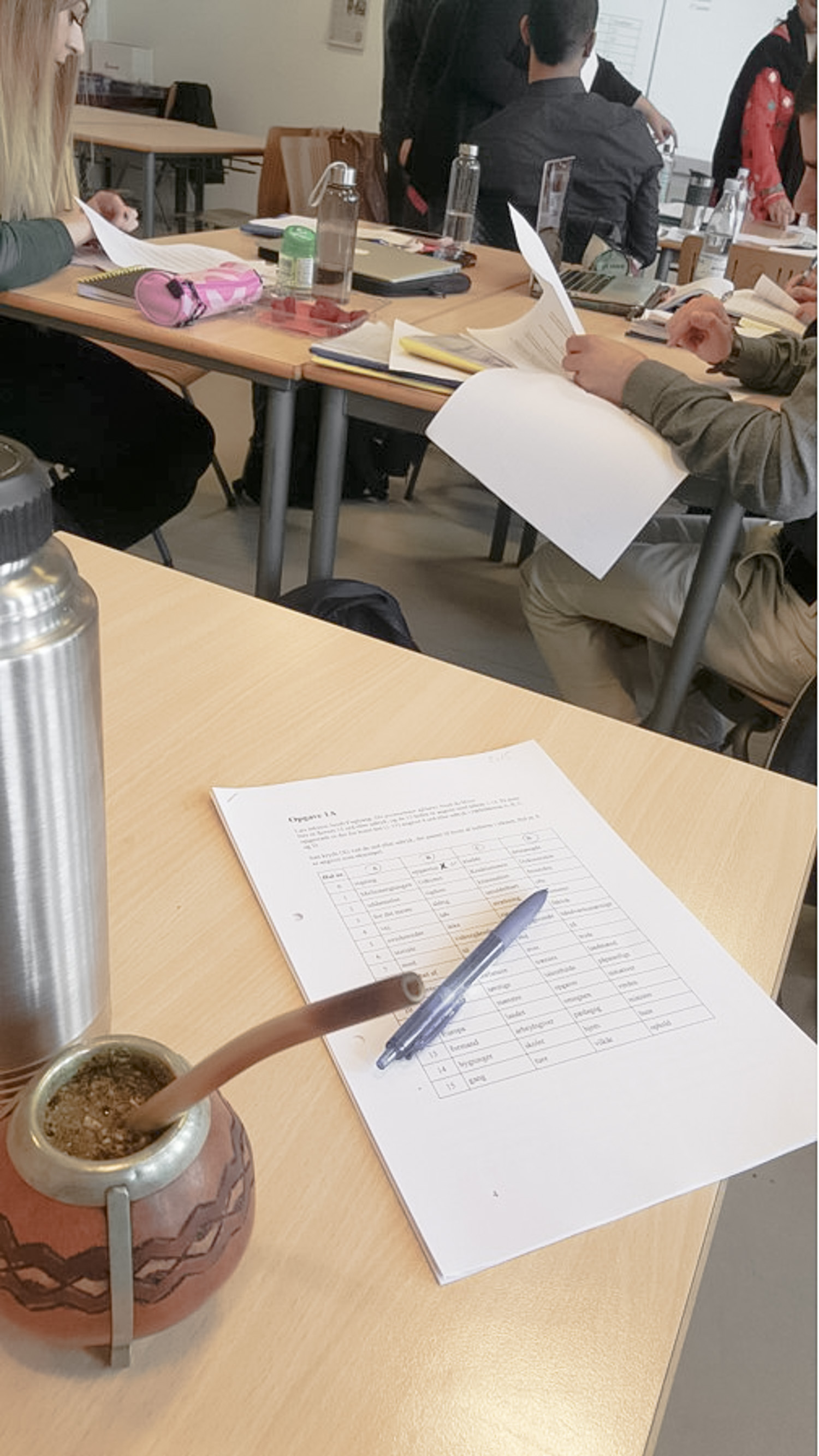 A school table with a paper and pen on it.