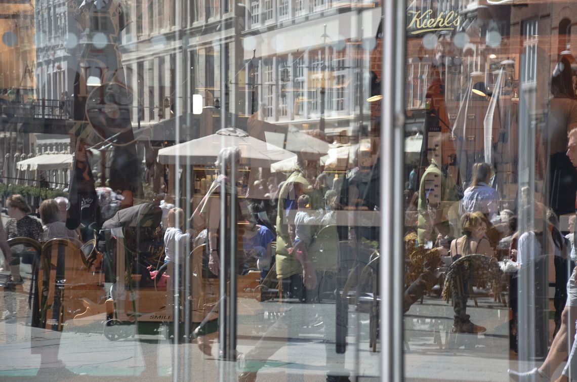 An entrance to a shop made of glass with people reflected in the glass