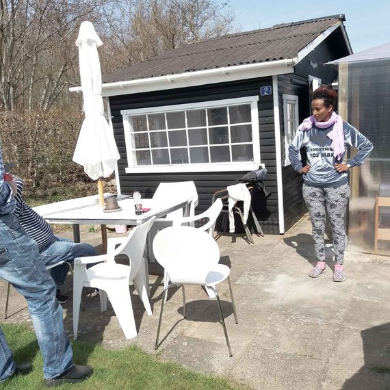 Three people standing outside a small black house with white windows