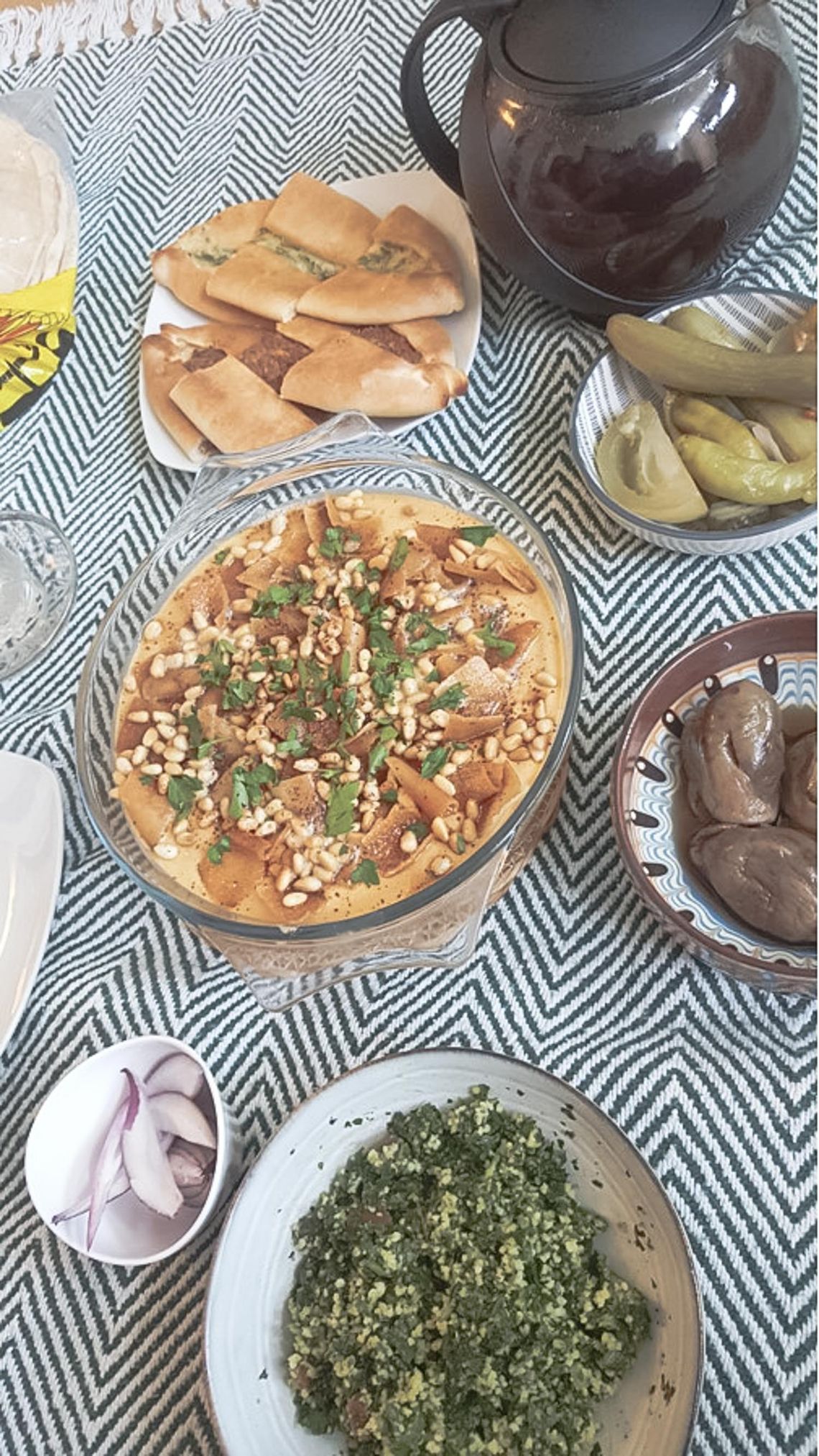 A blue tablecloth with arabic dishes on it.