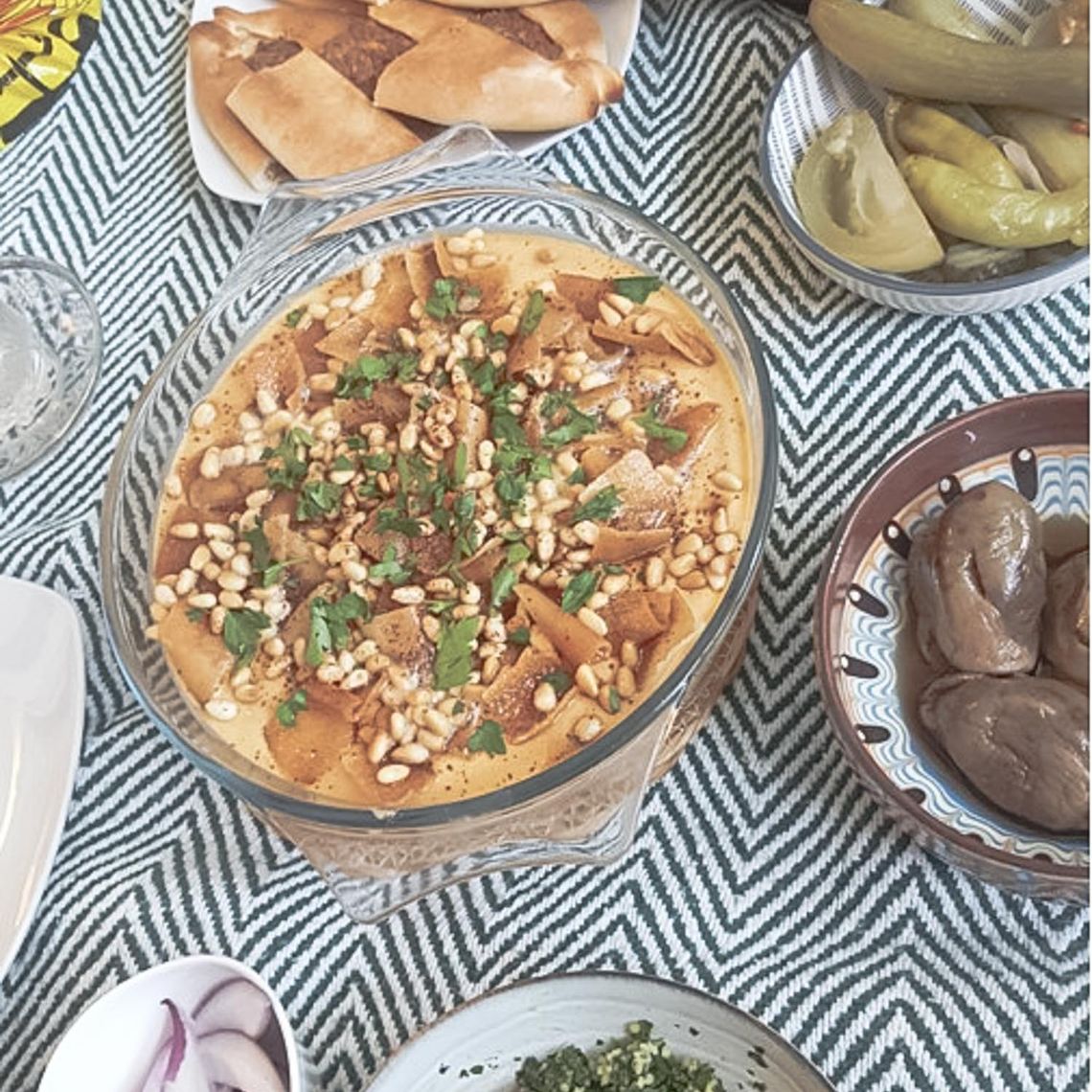 A blue tablecloth with arabic dishes on it.