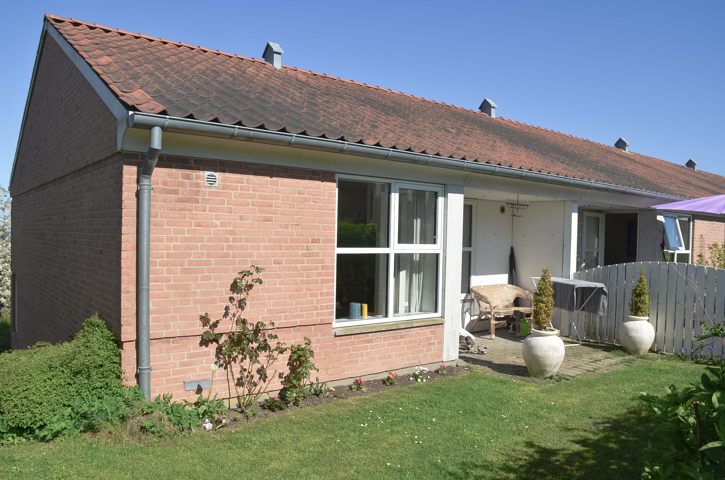 A house with red bricks, white windows and a lawn in front