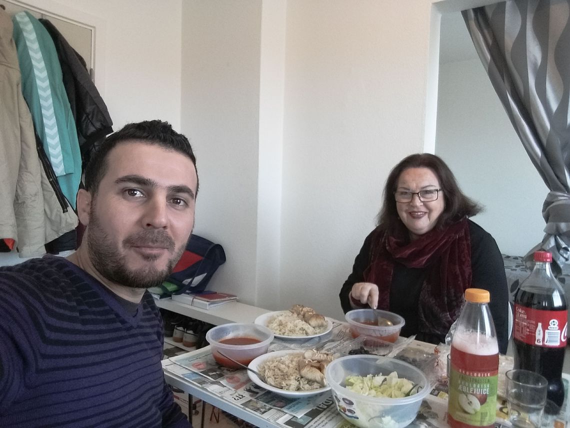 Abdulsalam and a woman sitting at a table filled with dishes and juice and coca cola