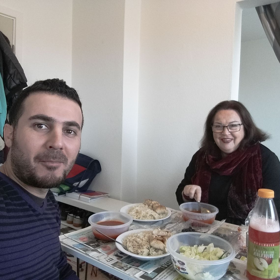Abdulsalam and a woman sitting at a table filled with dishes and juice and coca cola