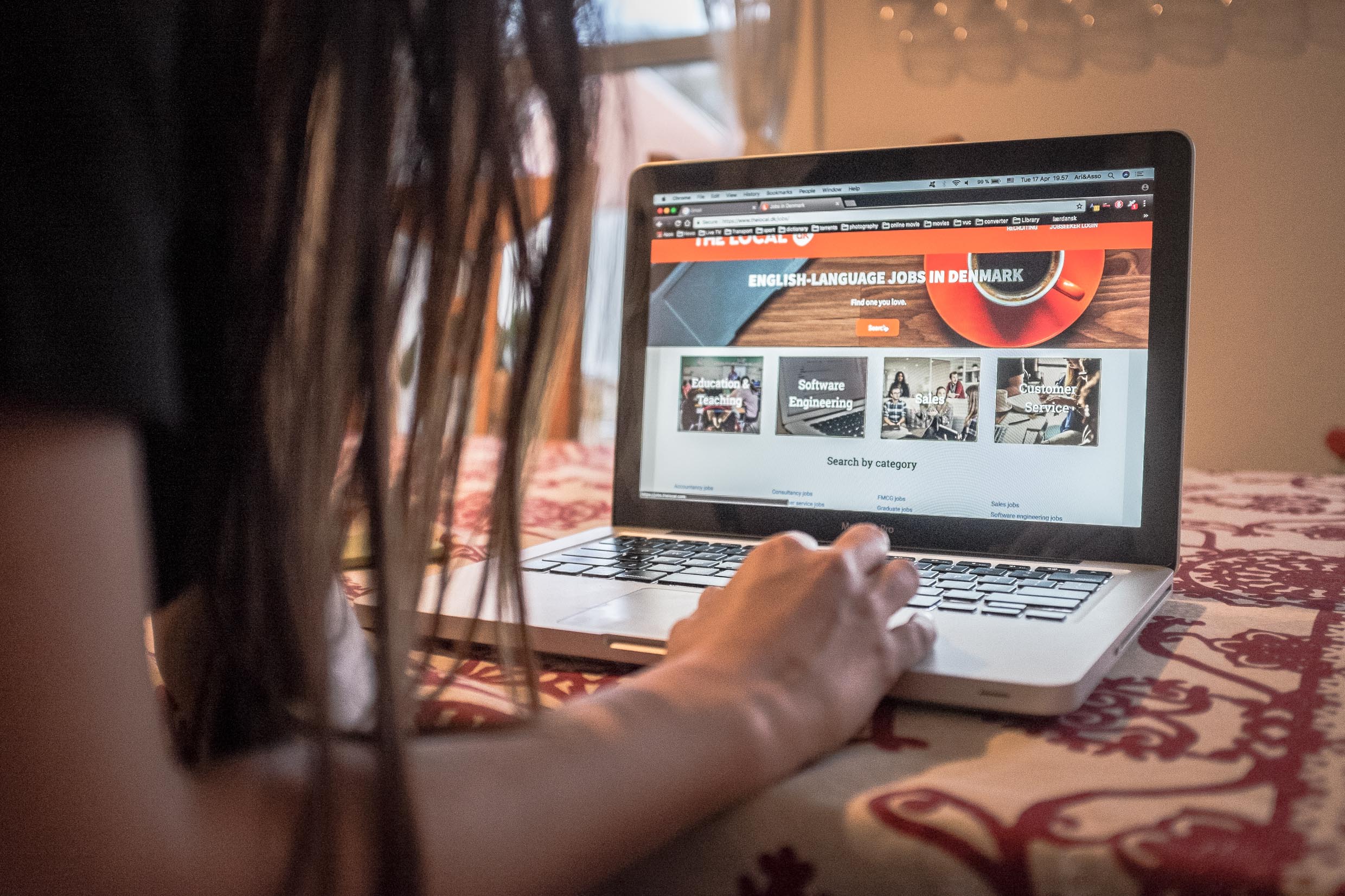 Arina sitting in front of a computer looking at a website saying English-language jobs in Denmark