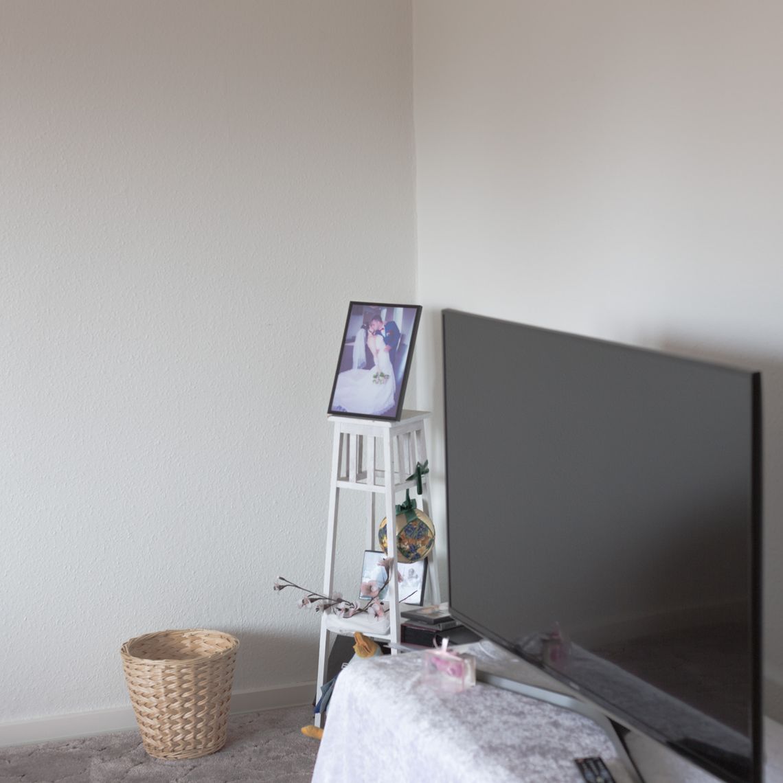 A television and a wedding photo in the corner of a white room.