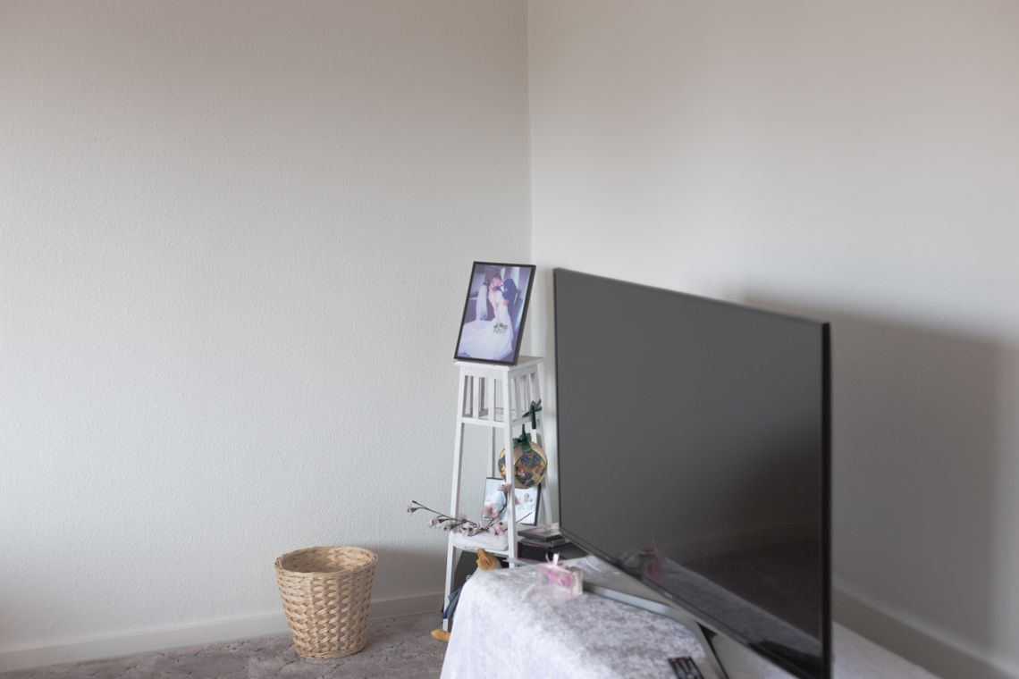 A television and a wedding photo in the corner of a white room.