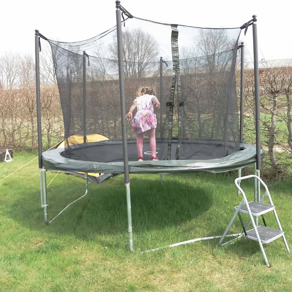 A small girl jumping on a trampoline standing on grass