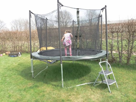 A small girl jumping on a trampoline standing on grass