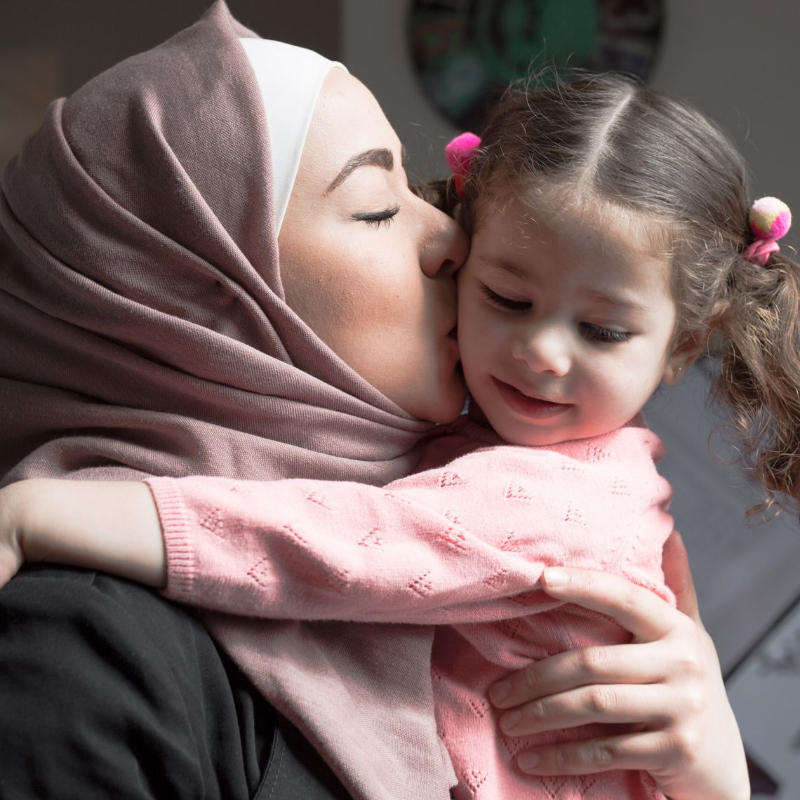 Wael's wife holding and kissing their daughter