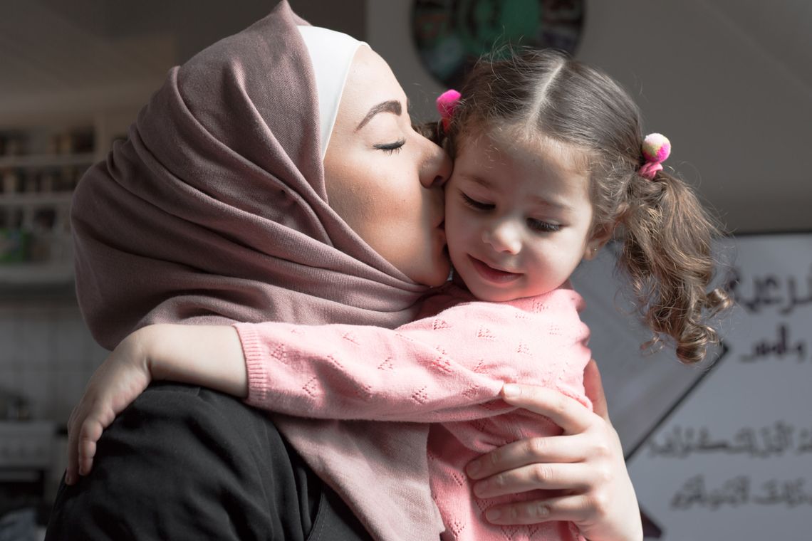 Wael's wife holding and kissing their daughter